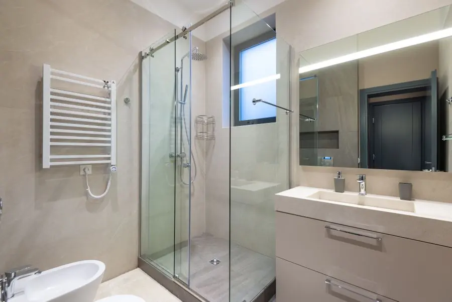 Kamar mandi modern dengan pintu kaca shower dan jendela kecil