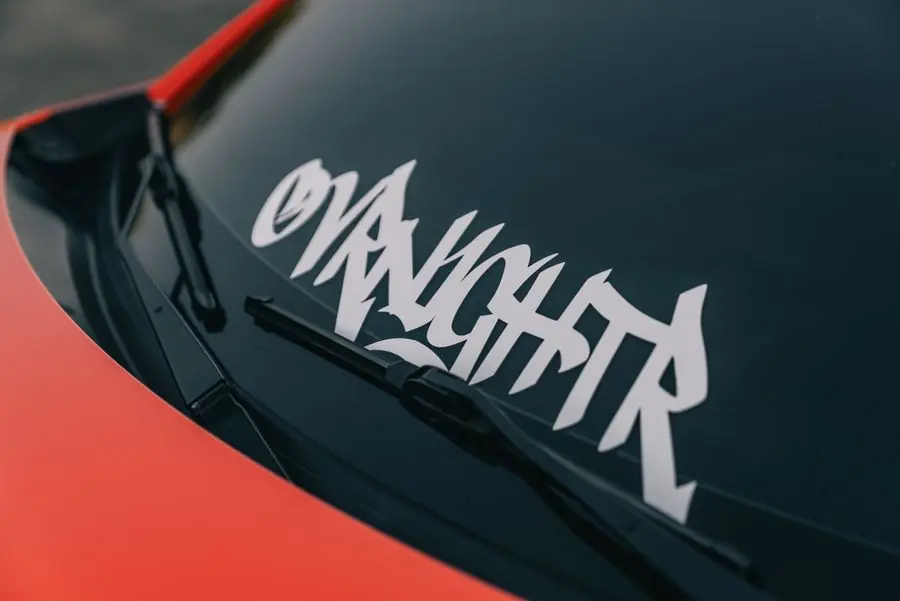 Sticker vinyl putih hasil cutting berbentuk huruf pada kaca mobil