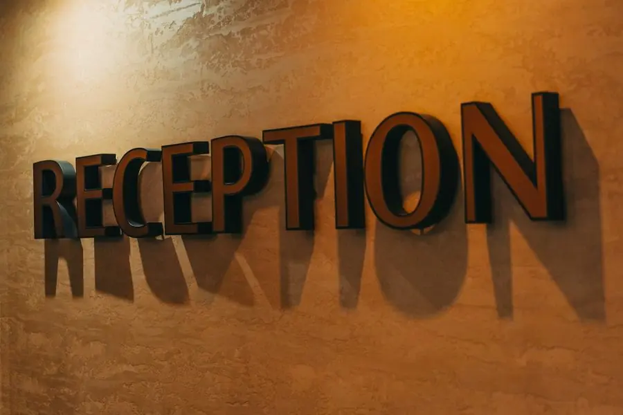 Huruf timbul tiga dimensi bertuliskan RECEPTION pada dinding lobi