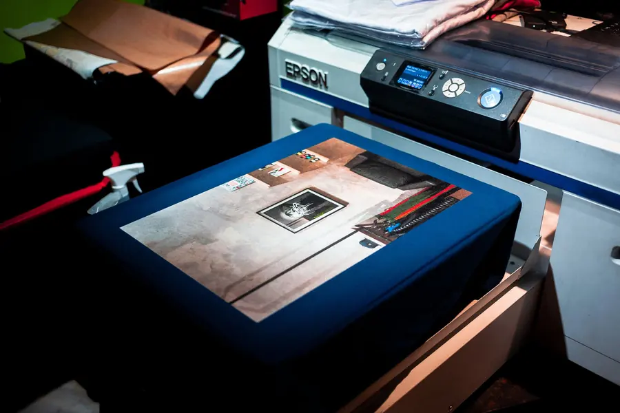 Printer digital sedang mencetak desain pada media berwarna biru